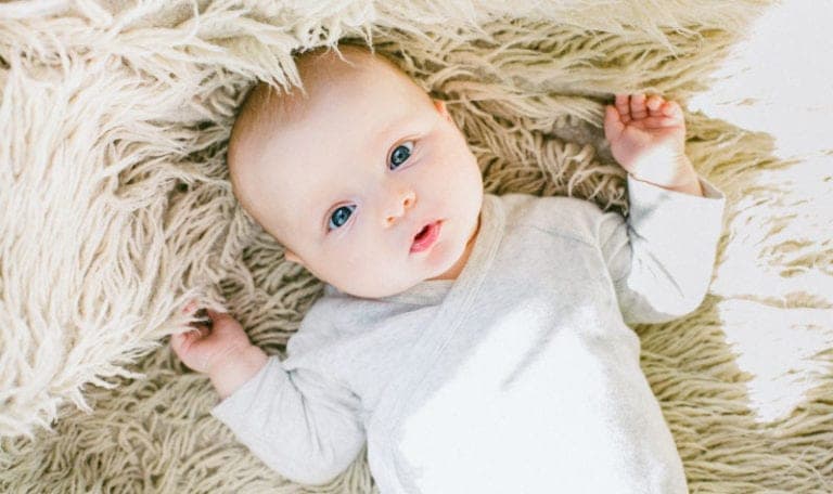 Aerial view of a bald baby on a furry blanket about to get his baby teeth
