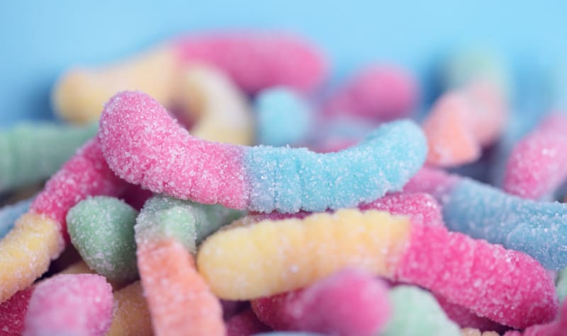 Closeup colorful sour gummy worms that are one of the worst Halloween treats